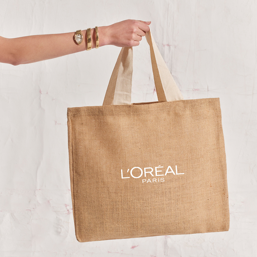 A stylish woman’s hand holding a branded L’Oréal gift bag, representing luxury corporate gifts for clients.