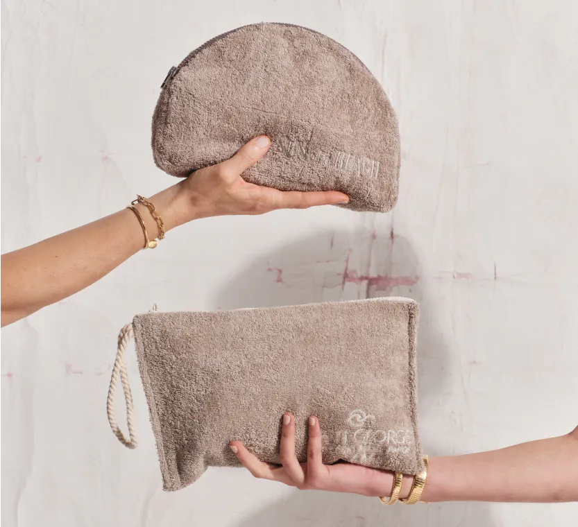 Two elegant women's hands holding luxury pouches, a sophisticated complimentary gift for hotel guests