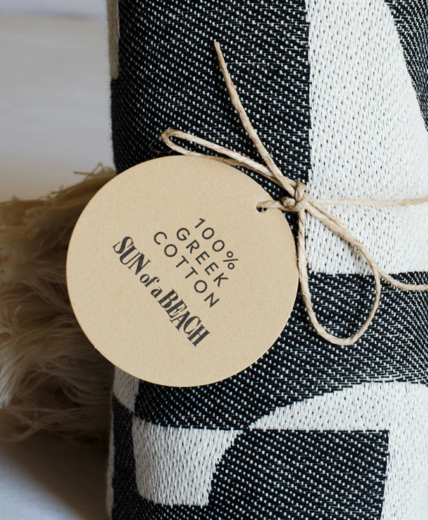 A luxurious beach towel made of Greek cotton, unpacked from a welcome gift bag, showcasing Sun of a Beach's premium guest offerings.
