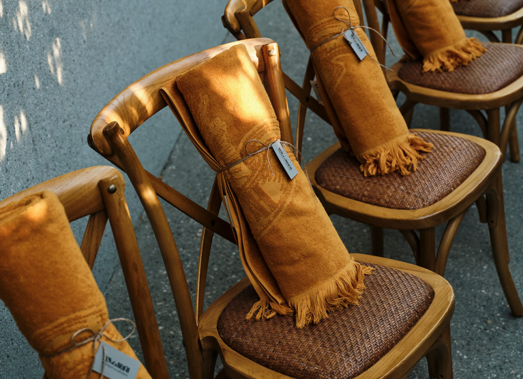 Elegant brown luxury towels are thoughtfully arranged on wooden chairs as gifts for guests attending this special event.